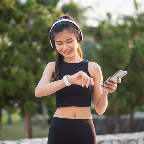 Active woman tracking fitness with smartwatch and phone outdoors